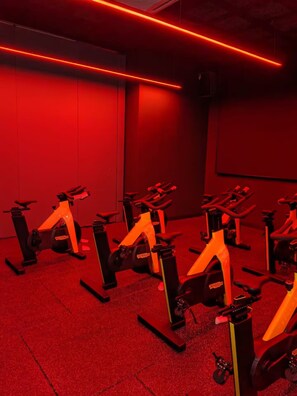 A room with multiple stationary bikes arranged in rows, red ambient lighting, and a carpeted floor. - Skyline A43A-07 Heart of the city, new (Kuala Lumpur)