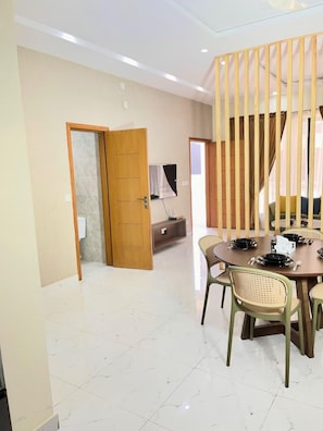 A dining area with a round table, chairs, and a wooden partition. - Cozy 1-bedroom apartment in superb Lahore with AC comfort (Lahore)