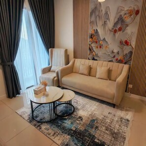 Ein Wohnzimmer mit einem beigen Sofa, zwei Sesseln, einem Couchtisch und einem dekorativen Wandgemälde.