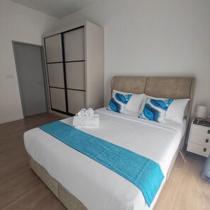 Ein ordentlich bezogenes Bett mit einer blauen Tagesdecke, zwei Kissen mit blauen Mustern und einem Satz weißer Handtücher.