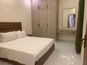 A bedroom with a large bed, a wardrobe, a mirror, and a bathroom with a toilet and sink. - Perfect 1-bedroom apartment with AC in soothing Lahore (Lahore)