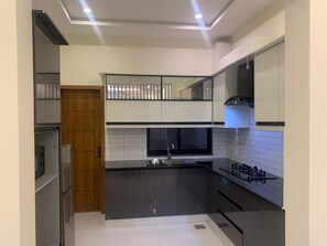 A modern kitchen with a built-in gas stove, a microwave, and a sink. - Perfect 1-bedroom apartment with AC in soothing Lahore (Lahore)