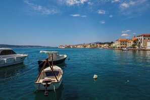 A marina with several boats docked, a clear blue sky, and buildings with red roofs along the waterfront. - Apartment Antonio, on the seafront with garden (Kaštel Stari)
