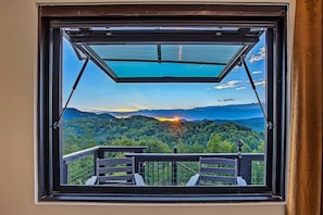 A room with a large window overlooking a forested mountain range. - Romantic Luxe Oasis•Private Pool•Mtn Views•Theater (Pigeon Forge)