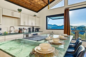 A modern kitchen with a marble countertop, built-in appliances, and a dining area with a view of the mountains. - Romantic Luxe Oasis•Private Pool•Mtn Views•Theater (Pigeon Forge)