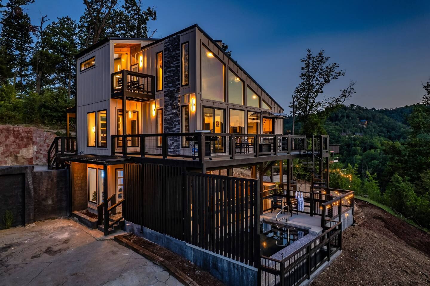 A multi-level modern house with a balcony, a pool, and a stone facade.