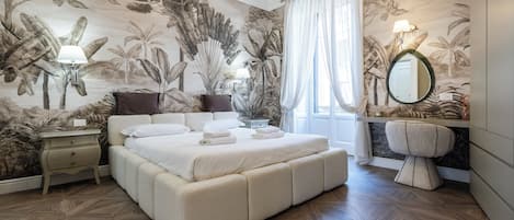 A bedroom with a large bed, a nightstand, a mirror, and a wall with a tropical mural.