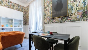 Ein Essbereich mit einem schwarzen Tisch, grünen Stühlen und einem weißen Schrank mit Regalen.