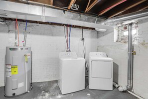 A laundry room with two washing machines, a water heater, and exposed ductwork. - Olde Towne East Townhouse | Minutes to Downtown (Columbus)