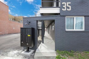 Un bâtiment dont la façade porte le numéro « 35 », avec une boîte aux lettres et un chemin de béton menant à une porte.