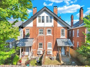 A two-story brick house with a front porch, a covered patio, and a fenced backyard. - Olde Towne East 4BR Townhome Near East Market (Columbus)