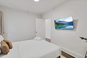 A hotel room with a bed, a television mounted on the wall, and a door leading to another room. - Olde Towne East 4BR Townhome Near East Market (Columbus)
