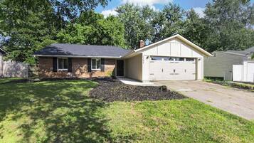 A single-story house with a garage, a front lawn, and a brick exterior.