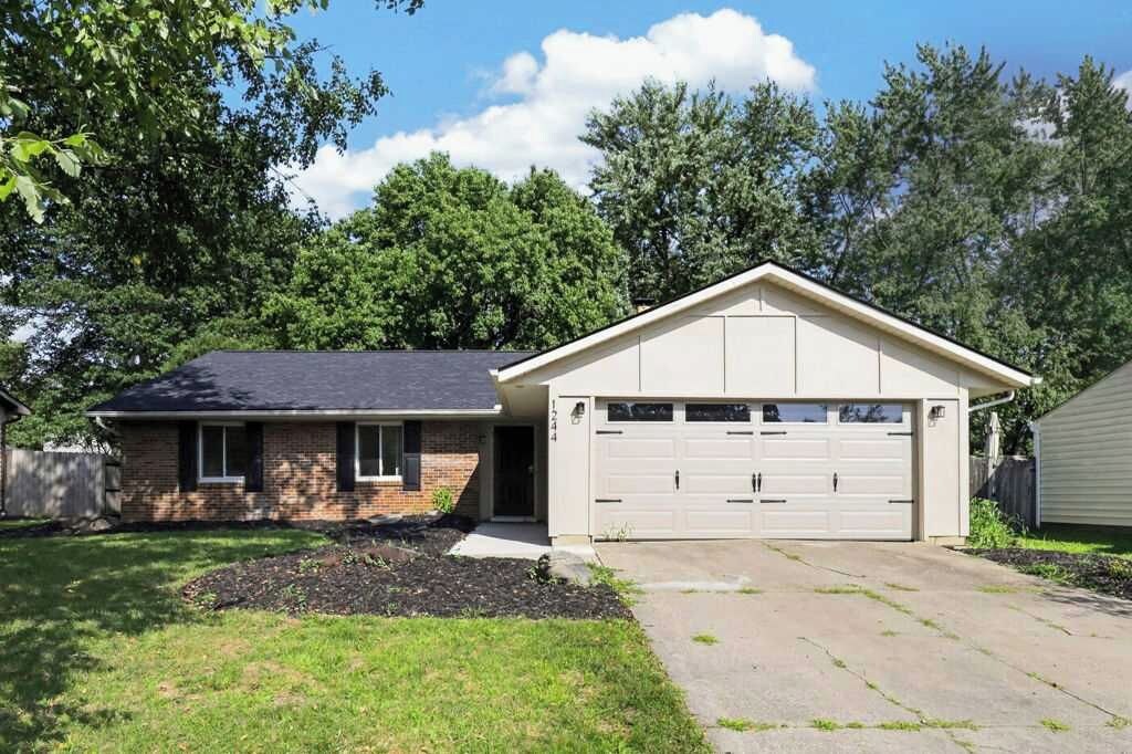 A single-story house with a garage, a front yard with a lawn and a small garden bed, and a wooden fence in the background.