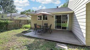 A patio with a table and chairs, a sliding glass door, and a small deck. - Cozy Reynoldsburg Home with Fireplace & Garage (Reynoldsburg)