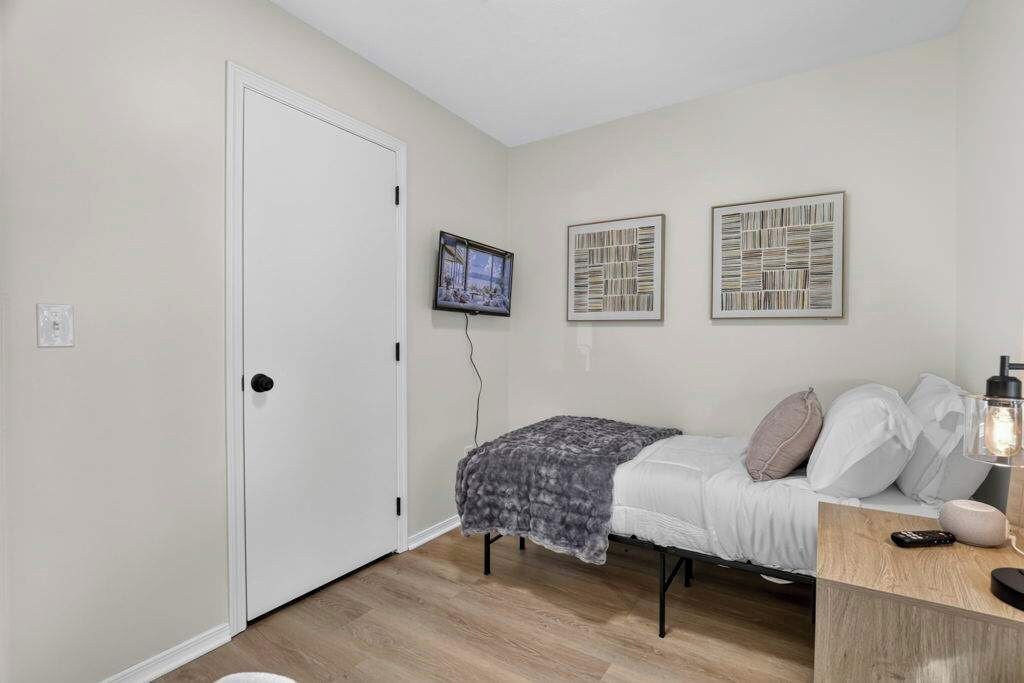 A bedroom with a bed, a television, and artwork on the wall.