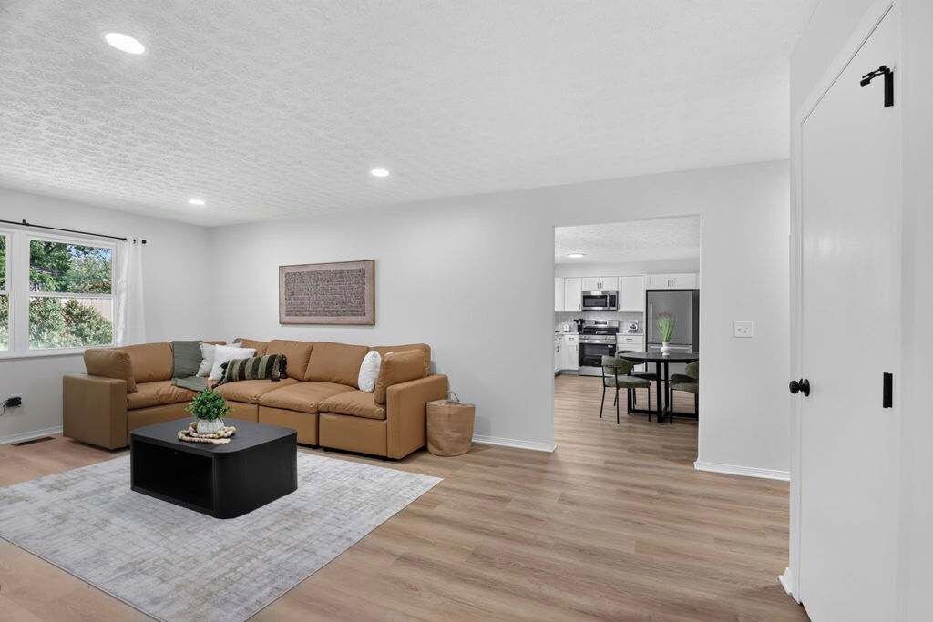 A modern living room with a sofa, coffee table, and a view into the kitchen.