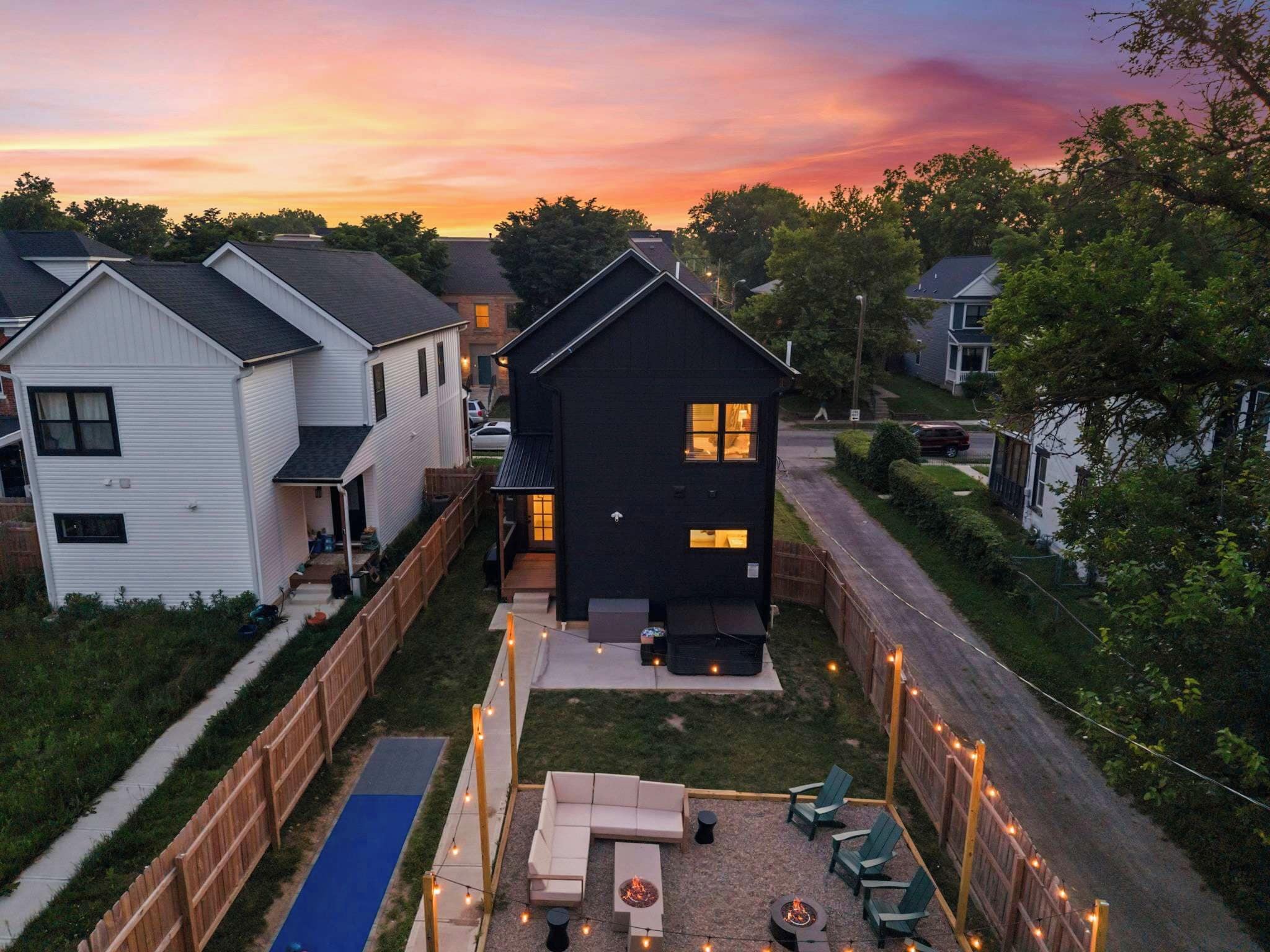 A residential property with a fenced backyard, a patio area with outdoor furniture, and a visible fire pit.