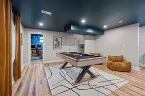A pool table in a room with wooden flooring and a geometric rug. - FUNtastic Home! | 5 BR - Hot Tub + Game Room! (Columbus)
