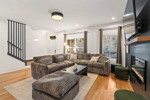 A modern living room with a sectional sofa, a coffee table, and a fireplace. - FUNtastic Home! | 5 BR - Hot Tub + Game Room! (Columbus)