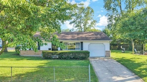 Een gelijkvloers huis met garage, voortuin en boom.