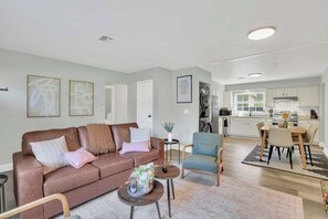Een moderne woonkamer met een bruine bank, een salontafel, en een eethoek met een tafel en stoelen.