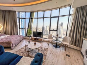 Une chambre d’hôtel moderne dotée d’un grand lit, d’une télévision, d’un coin repas et offrant une vue sur la ville.