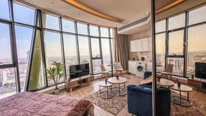 A modern hotel room with a large bed, a TV, a dining area, and a kitchen. - Best for get away & Peaceful Haven by Flouri F282O (Seef)