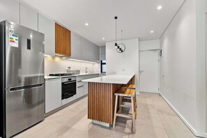 Eine moderne Küche mit einem Edelstahl-Kühlschrank, einem Einbauofen und einer Holz-Kochinsel mit Spüle.
