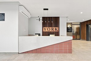 A reception desk with a sign that reads 'YORK' above it, a modern light fixture, and a signboard with directions to various facilities. - Luxe 2BR York | Ocean-View | AC | Balcony (Umhlanga)