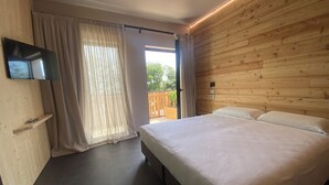 Een slaapkamer met een bed, gordijnen, een televisie en een houten wand.