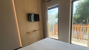 Een hotelkamer met een groot bed, een wandgemonteerde televisie en een schuifdeur naar een buitenbalkon.
