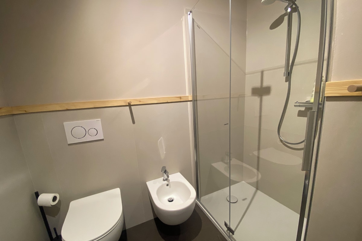Moderni kylpyhuone, jossa on wc, bidee ja lasiseinällä varustettu suihku.