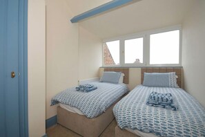 Ein Schlafzimmer mit zwei Betten, einem Fenster und einer Tür.