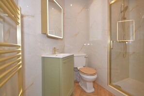Ein Badezimmer mit Toilette, Waschbecken, Spiegel und Duschkabine.