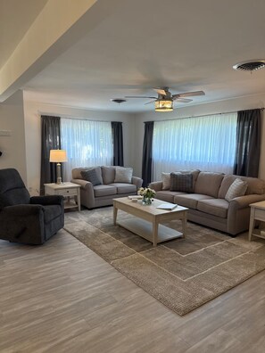 A modern living room with a sofa, armchair, coffee table, and a ceiling fan. - Welcome to Streator Hilltop - 3 bedroom home fully renovated and beautiful! (Streator)
