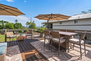 A deck with outdoor furniture, including chairs and a table, under large umbrellas. - Kahaluu Beach, 2-bed 2-bath, AC, steps to beach (Kailua-Kona)