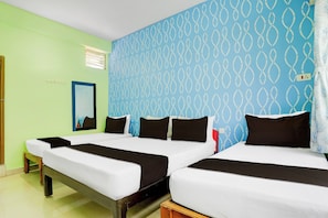 Ein Hotelzimmer mit zwei Betten, einem Fenster mit Jalousien, einem Spiegel an der Wand und einer Steckdose.