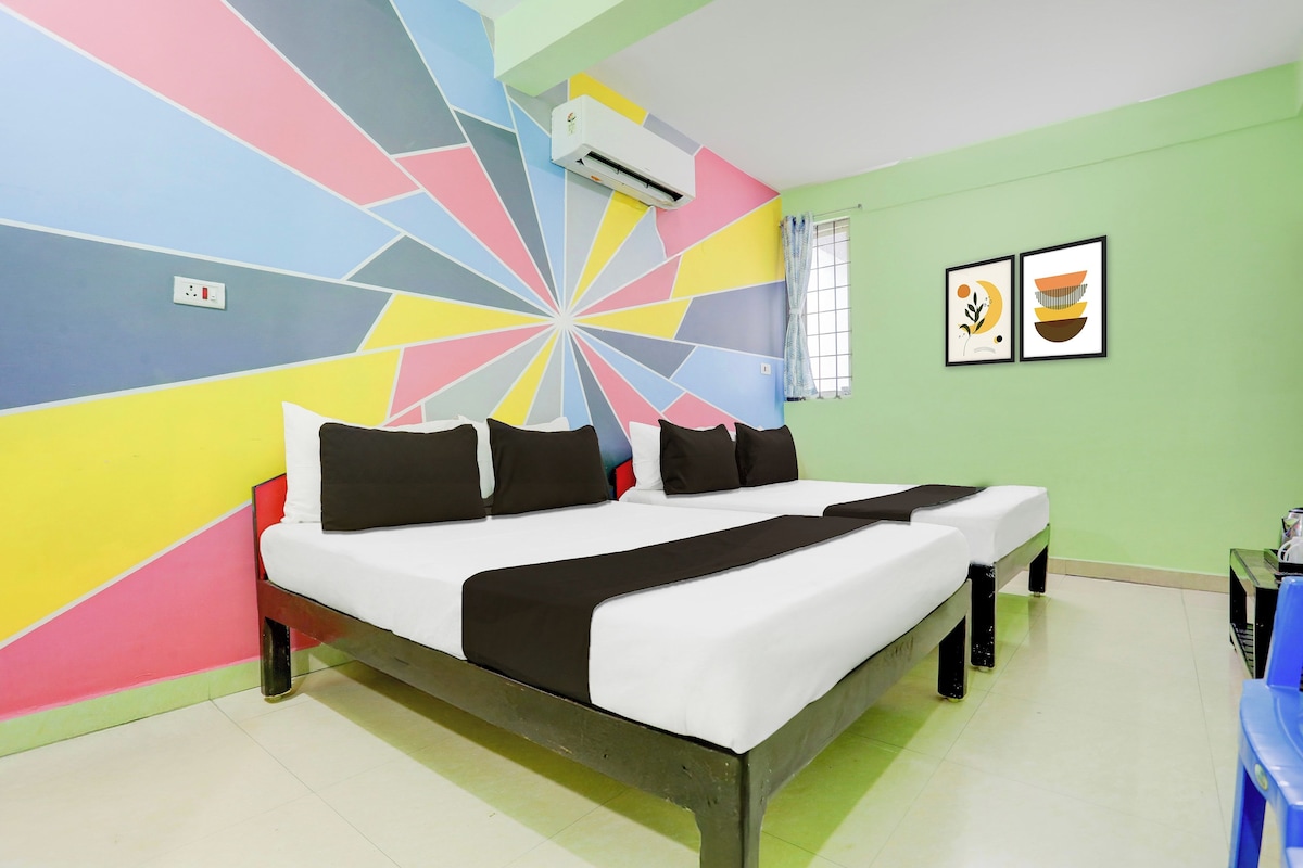 Ein Zimmer mit einem Bett, einer Wand mit farbigem geometrischem Muster, einer Klimaanlage und zwei gerahmten Kunstwerken an der Wand.