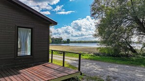 A wooden cabin with a deck, a view of a lake, and a pathway leading to the cabin. - Lakefront Champlain Duplex , King Bed & Bunk Bed w/ Kayaks, Pool & Fire Pit (Champlain)