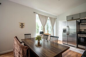 A modern kitchen with a large island, stainless steel appliances, and a dining area with a wooden table and chairs. - Lakefront Champlain Duplex , King Bed & Bunk Bed w/ Kayaks, Pool & Fire Pit (Champlain)