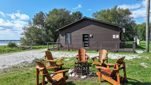A cabin with a gravel path leading to it, surrounded by greenery and trees. - Lakefront Champlain Duplex , King Bed & Bunk Bed w/ Kayaks, Pool & Fire Pit (Champlain)