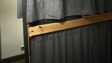 Una habitación con una cama de estructura de madera y cortinas grises.