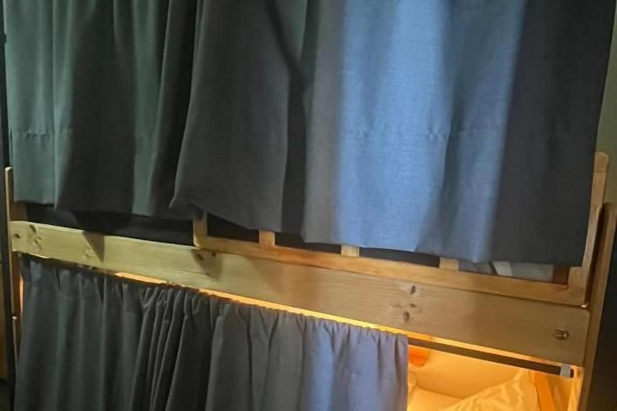 Una cama litera con cortinas, una mesita de noche y una lámpara.
