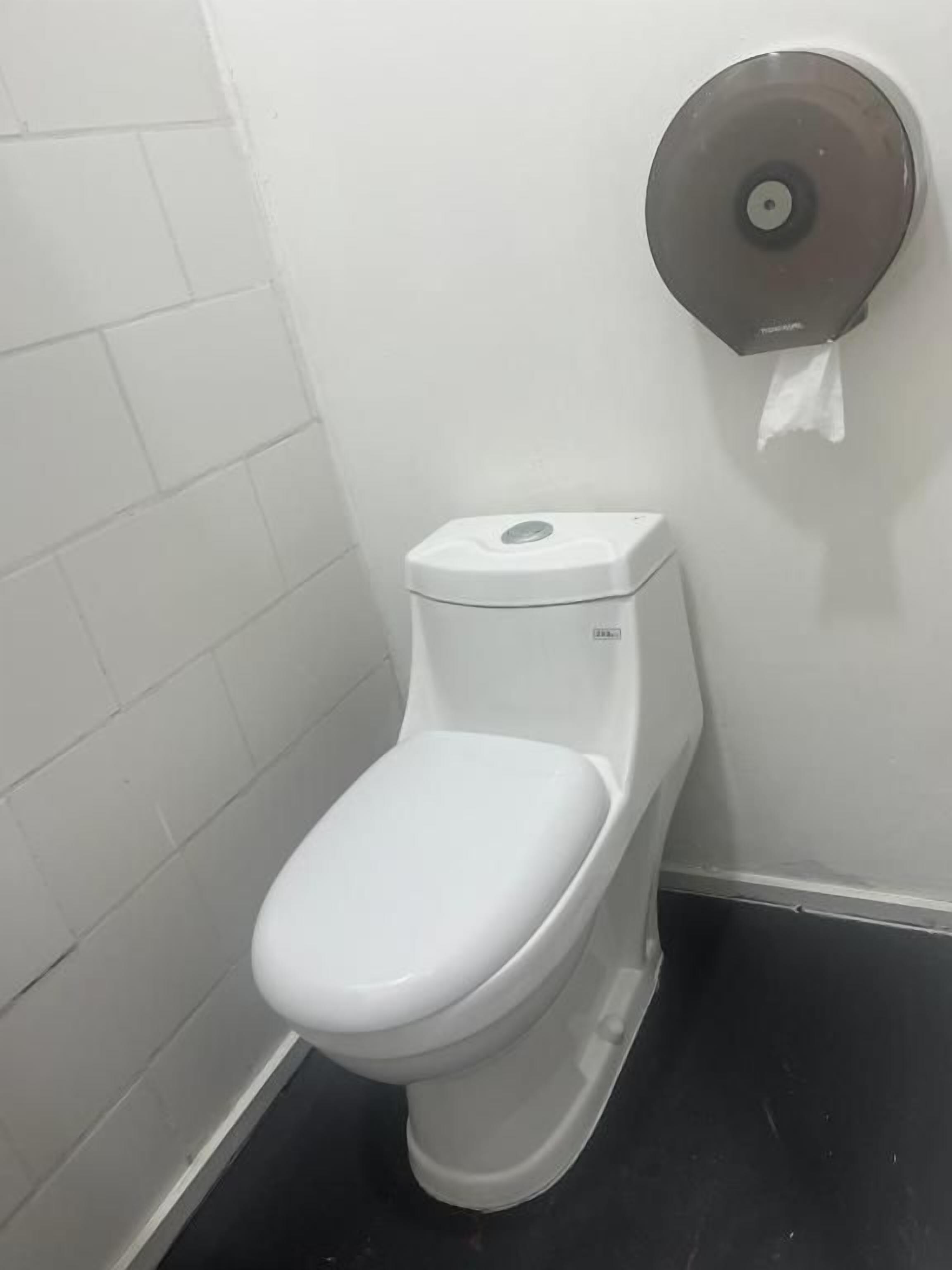 Un inodoro blanco con dispensador de papel de pared.