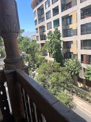 A multi-story building with balconies, a wooden railing, and a view of trees and a distant mountain.