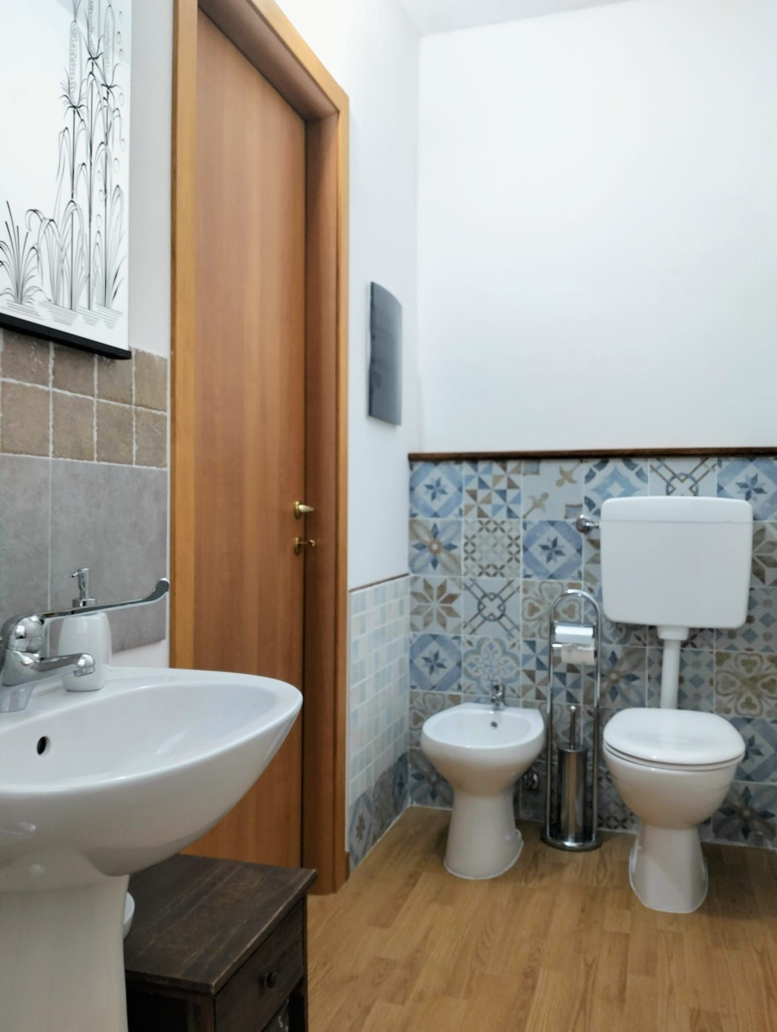 Une salle de bain avec une porte en bois, un lavabo blanc, un bidet et des toilettes.