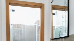 A bathroom with a glass shower door, a white sink, and a wooden vanity. - Vrbo Property (Forcola)