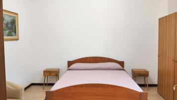 Quarto com cama de madeira, duas mesas de cabeceira, um guarda-roupa e um quadro pendurado na parede.