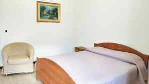 Ein Schlafzimmer mit einem Bett, einem Sessel und einem Gemälde an der Wand.